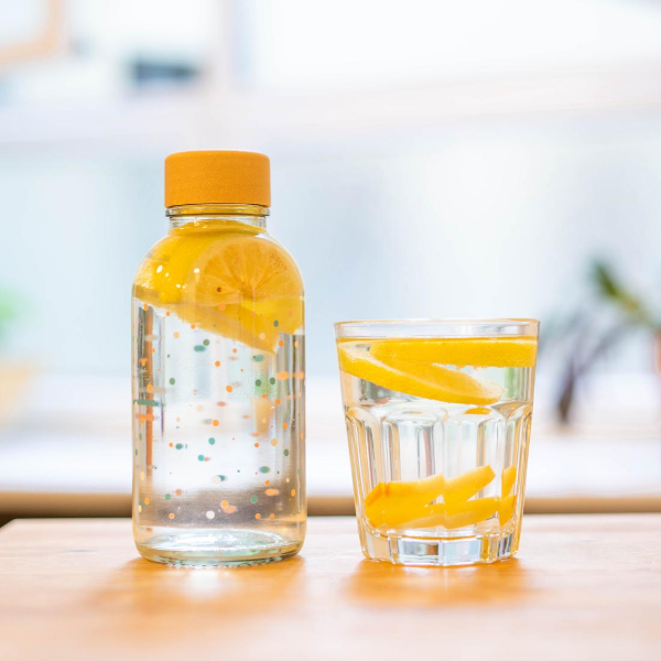 Drinkfles Flying Circles met sinaasappel naast een glas