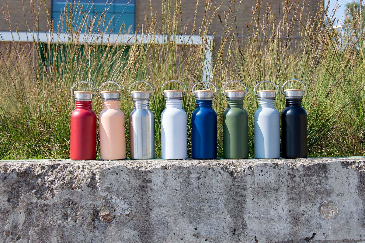 Drinkflessen Urban in verschillende kleuren op een betonnen muurtje