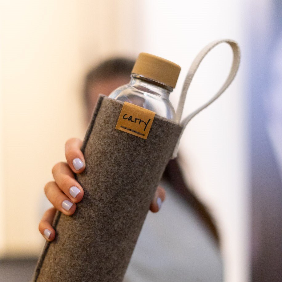 Drinkfles in naturel beschermhoes in de hand