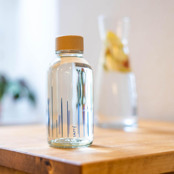 Drinkfles Rise Up op een houten tafel naast een karaf