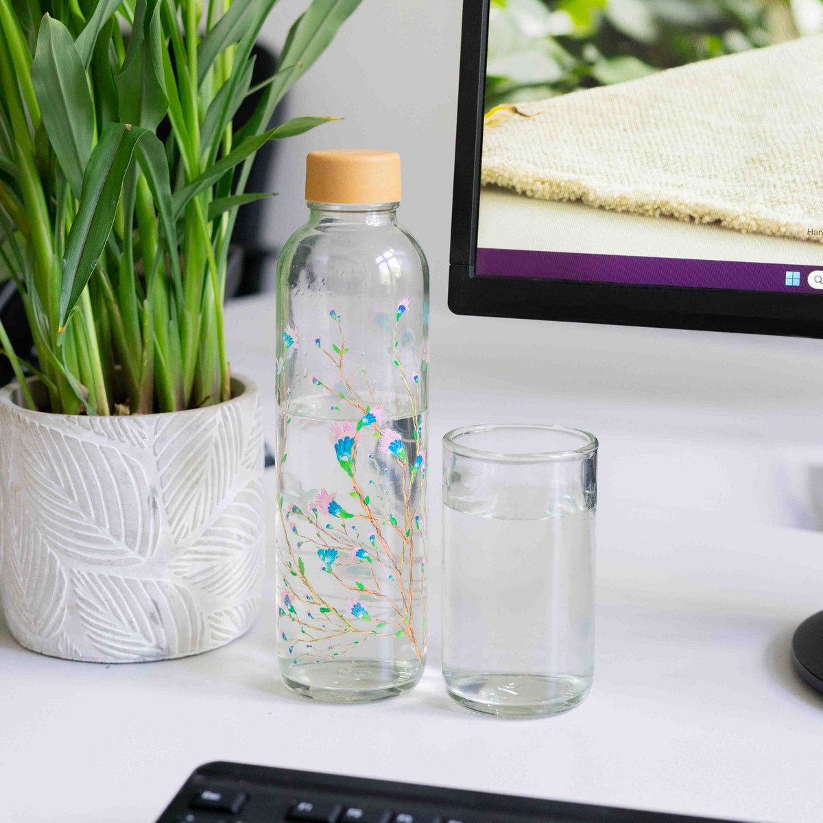 Drinkglas naast een CARRY-drinkfles op een bureau