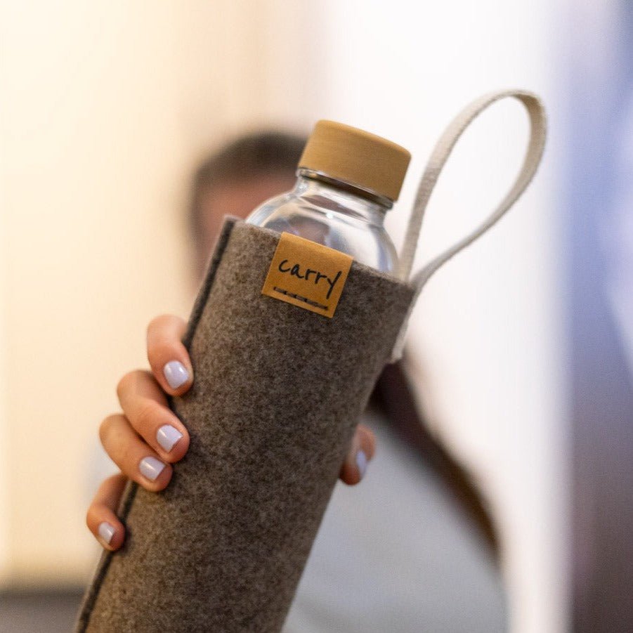Drinkfles in naturel vilten beschermhoes in de hand