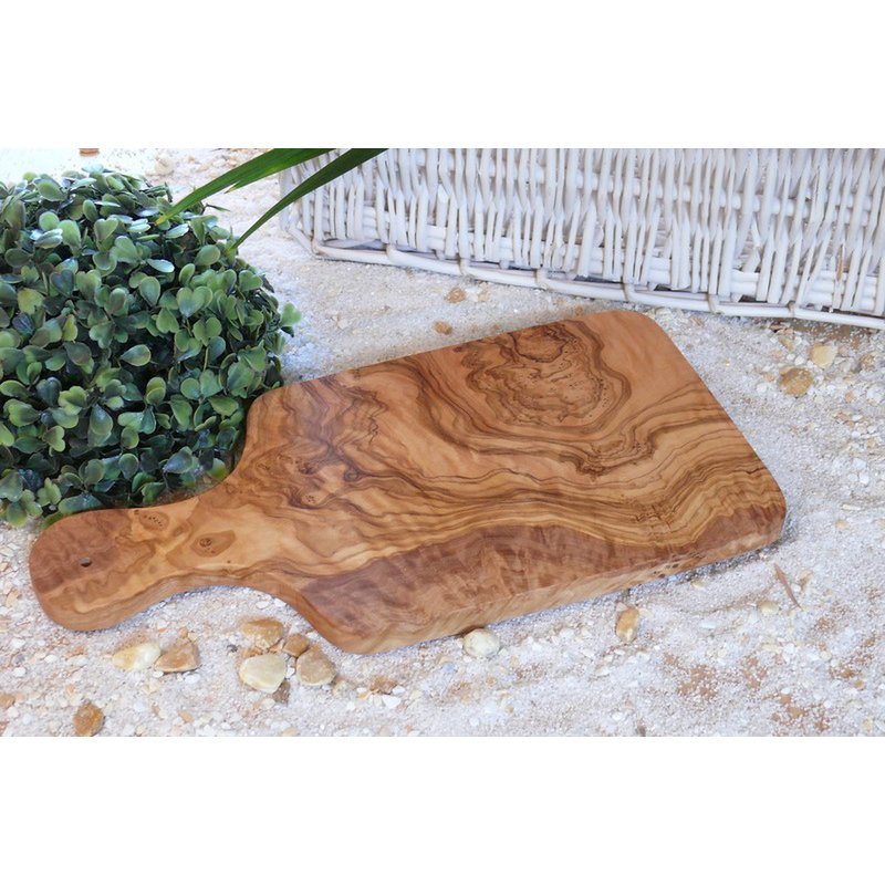 Ontbijtplank met handvat van olijfhout op wit zand met een plant