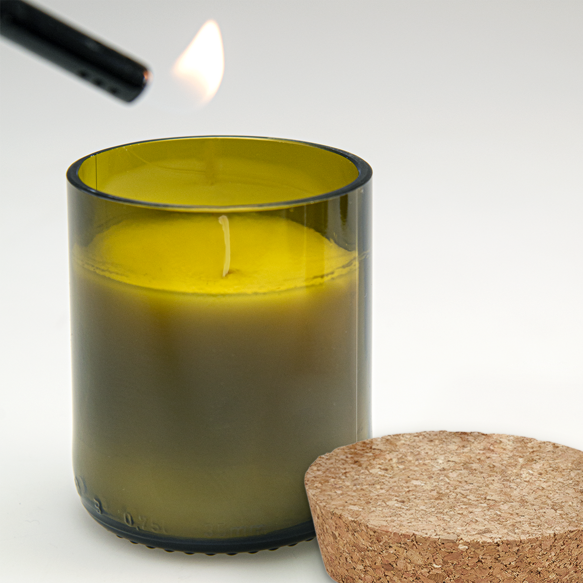Kaars in een olijfgroen glas van een wijnfles wordt aangestoken, met het kurkdeksel ernaast