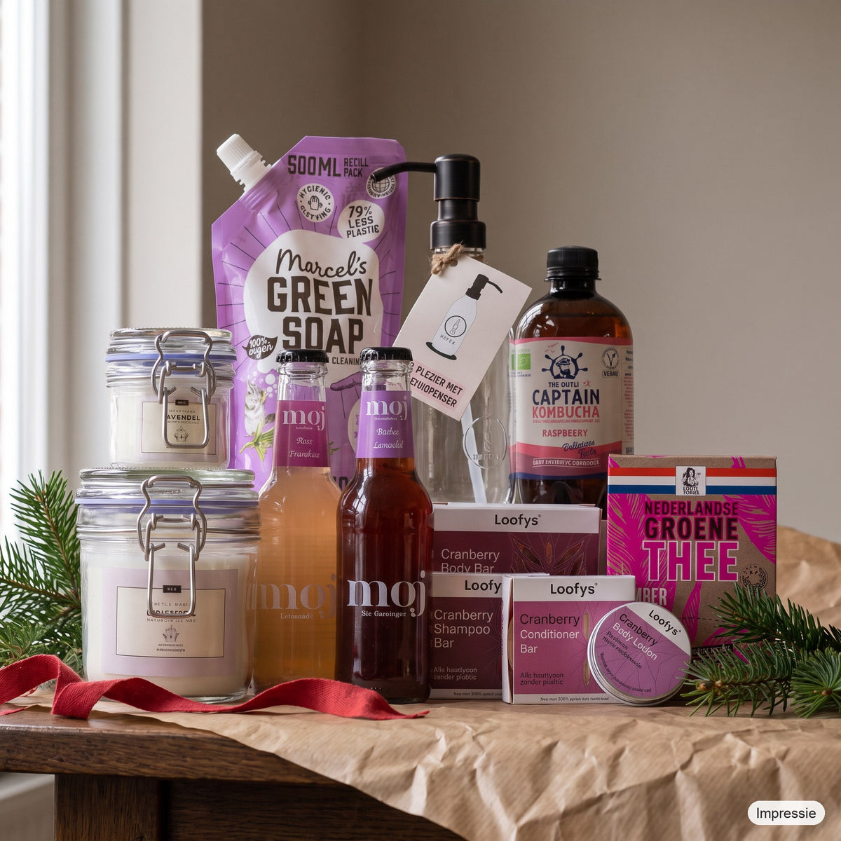 Feel Good Kerstpakket - M - Paars op een houten tafel met kraftpapier, dennentakken en een rood lint (impressie)