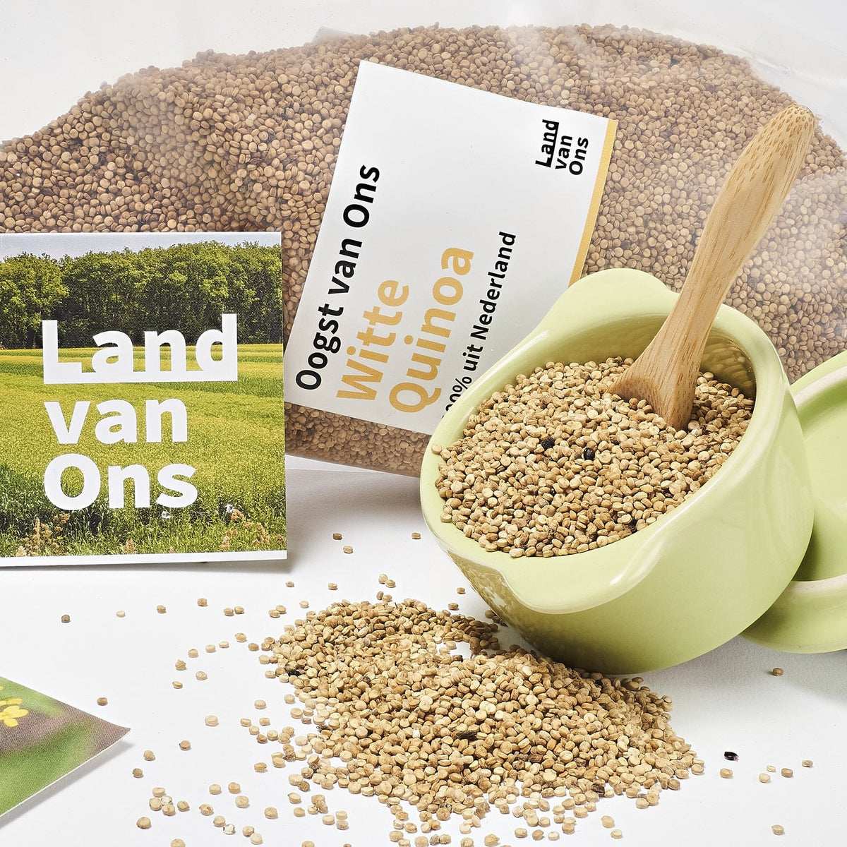 Witte quinoa in een schaaltje met een houten lepel, naast de zak van Land van Ons