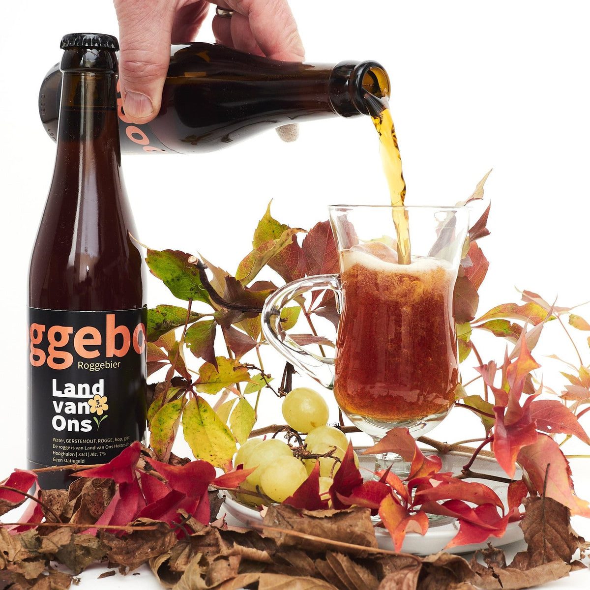 Roggebock wordt in een glas geschonken, tussen herfstbladeren