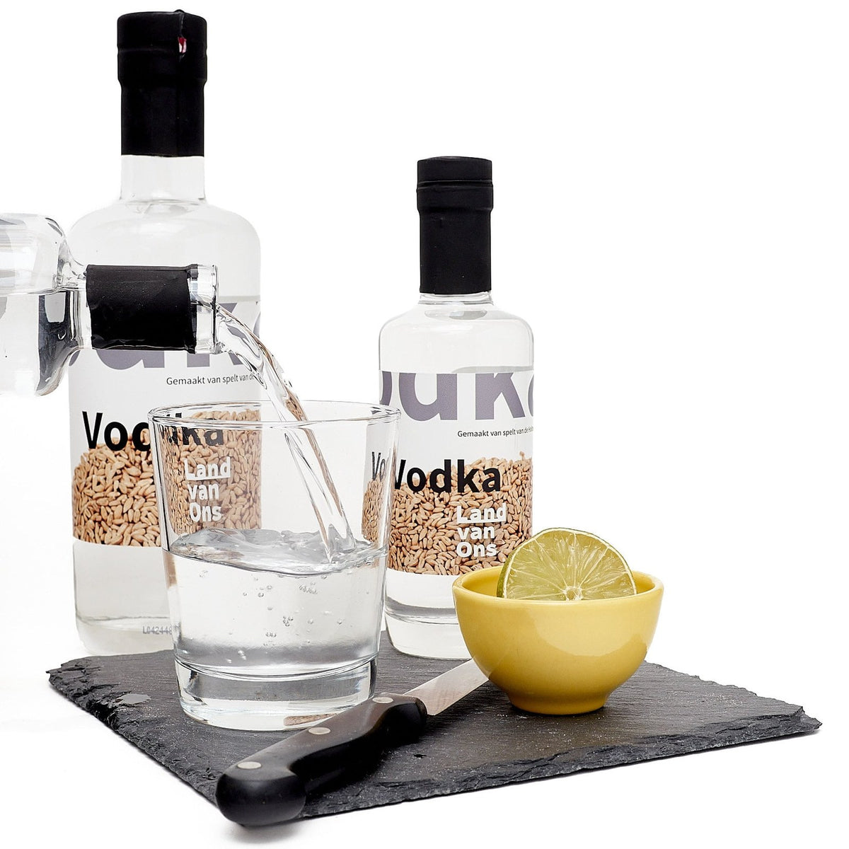 Vodka van Land van Ons wordt in een glas met ijs geschonken, met een halve limoen