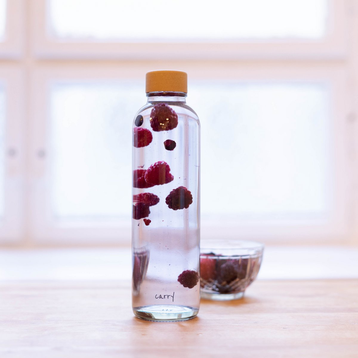 Drinkfles Pure met water en bessen bij het raam