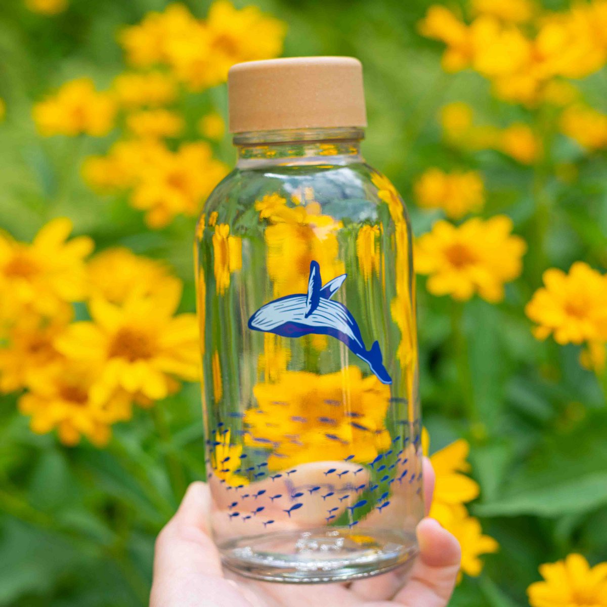 Drinkfles Ocean Lover in de hand voor gele bloemen