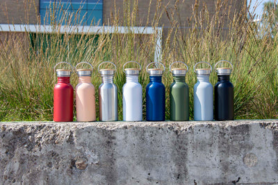 Drinkflessen Urban in verschillende kleuren op een betonnen muurtje
