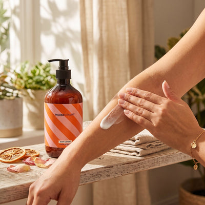 Bodylotion Groene thee op een houten bank bij het raam, iemand smeert lotion op de arm