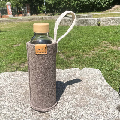 Drinkfles in naturel beschermhoes op een steen in het gras