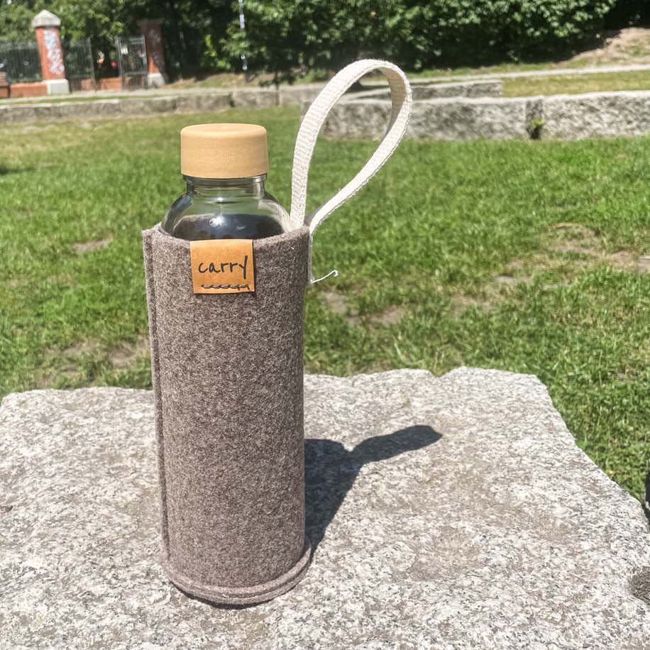 Drinkfles in naturel beschermhoes op een steen in het gras