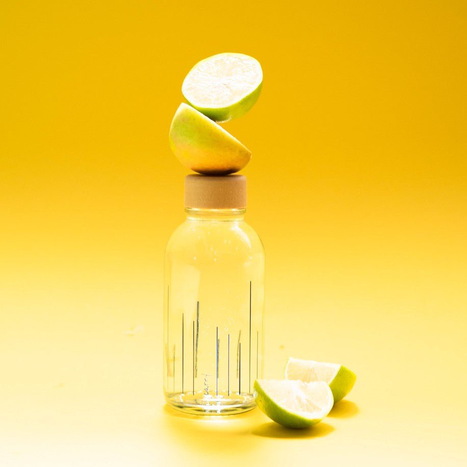 Drinkfles Rise Up met schijfjes citrus op een gele achtergrond