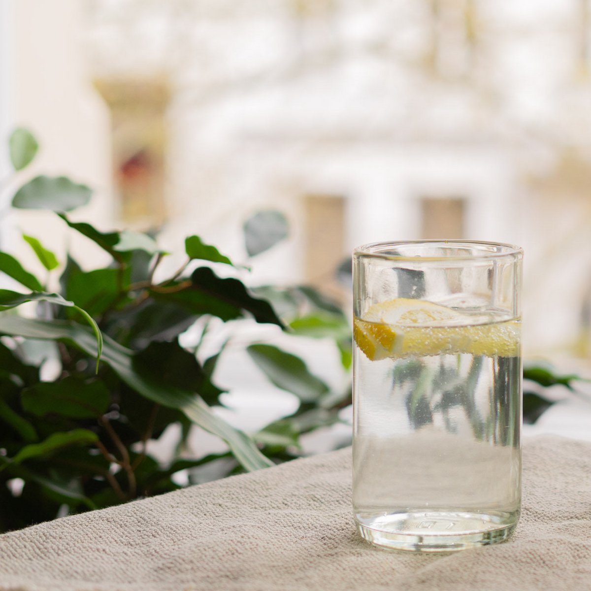Drinkglas van 300 ml met water en citroen op tafel bij het raam