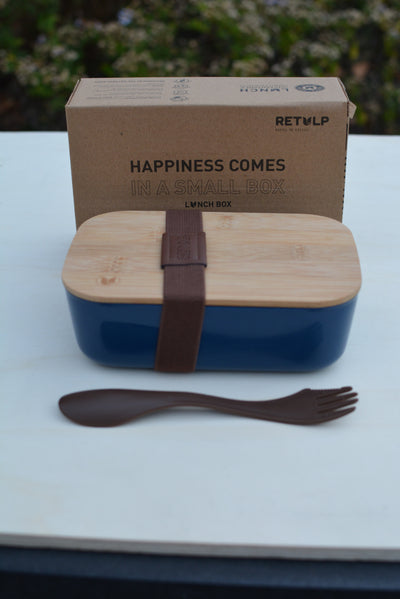 Blauwe lunchbox met bamboe deksel en spork op tafel, met de doos erachter