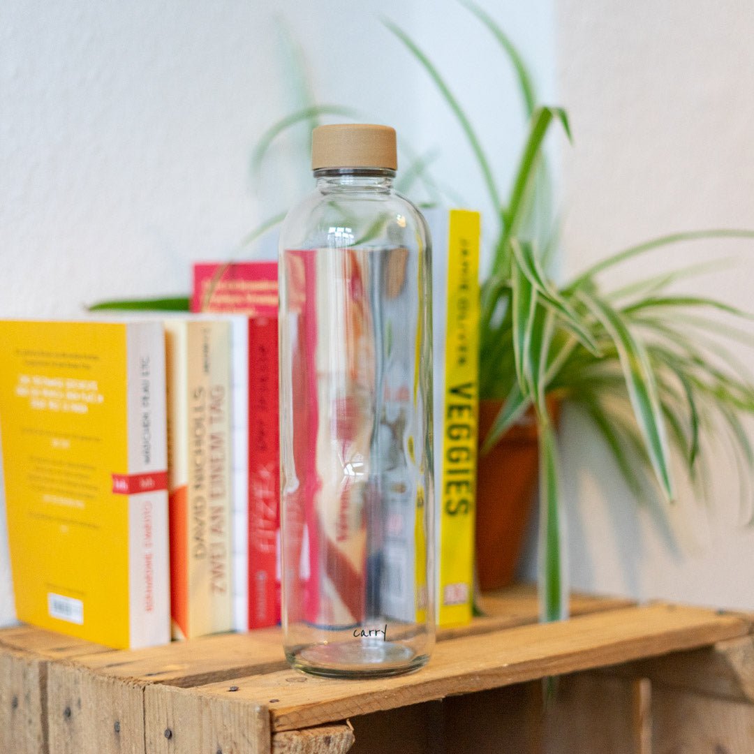Drinkfles Pure op een houten kist naast boeken en een plant