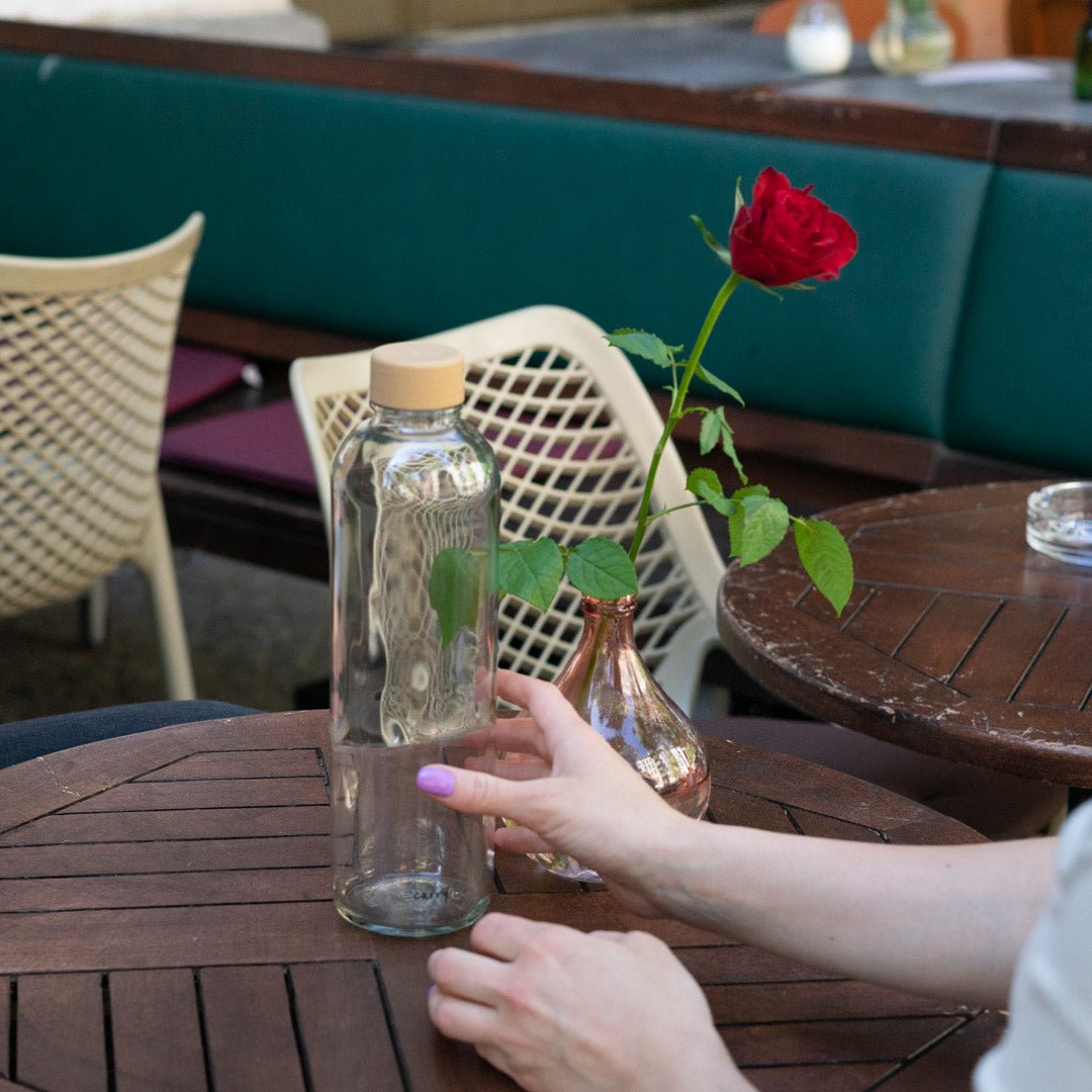 Drinkfles Pure in handen aan een tafel