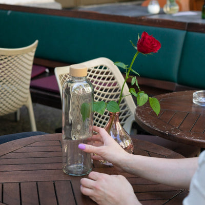 Drinkfles Pure in handen aan een tafel