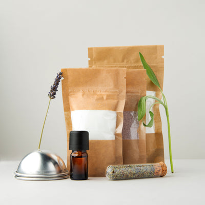 Zakjes met ingrediënten, bruisbalmal, flesje lavendelolie en reageerbuisje met gedroogde lavendel