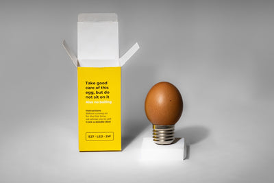 Egglamp Brown op een wit voetje naast de open doos
