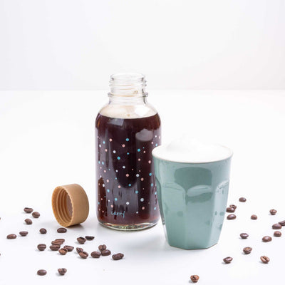 Drinkfles Flying Circles naast koffiebonen en een beker