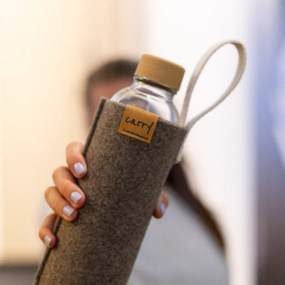 Drinkfles in naturel vilten beschermhoes in de hand