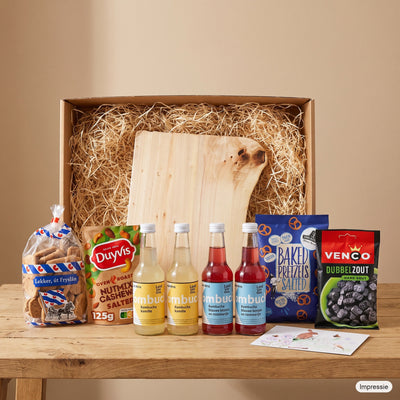 Impressie van het grote borrelpakket met de doos, de robuuste borrelplank en de lekkernijen op tafel