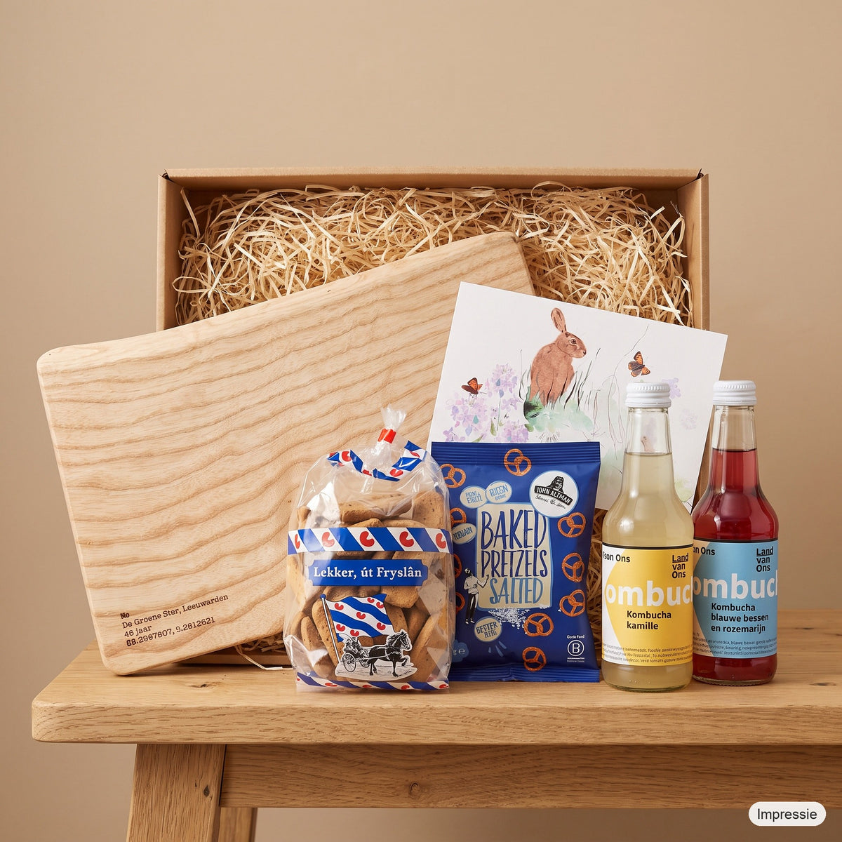 Impressie van het borrelpakket voor twee met de doos, de kleine borrelplank en de lekkernijen op tafel