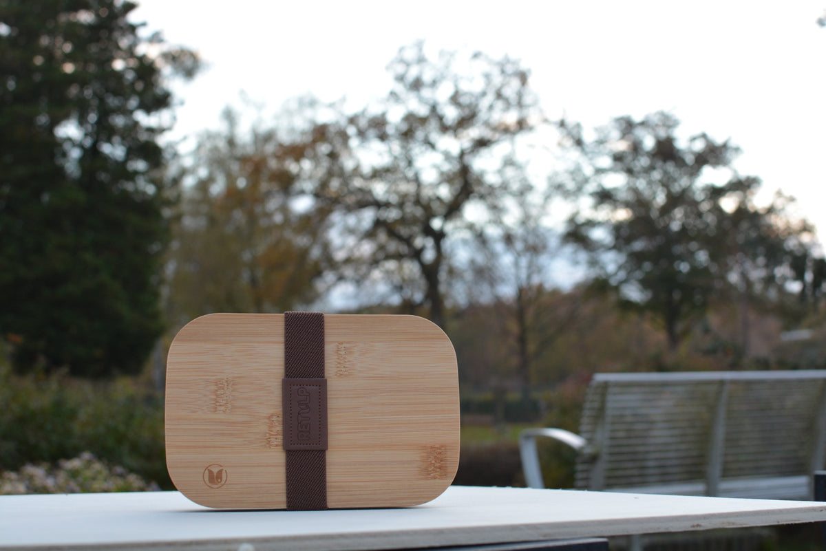 Lunchbox met bamboe deksel en elastische band buiten op tafel