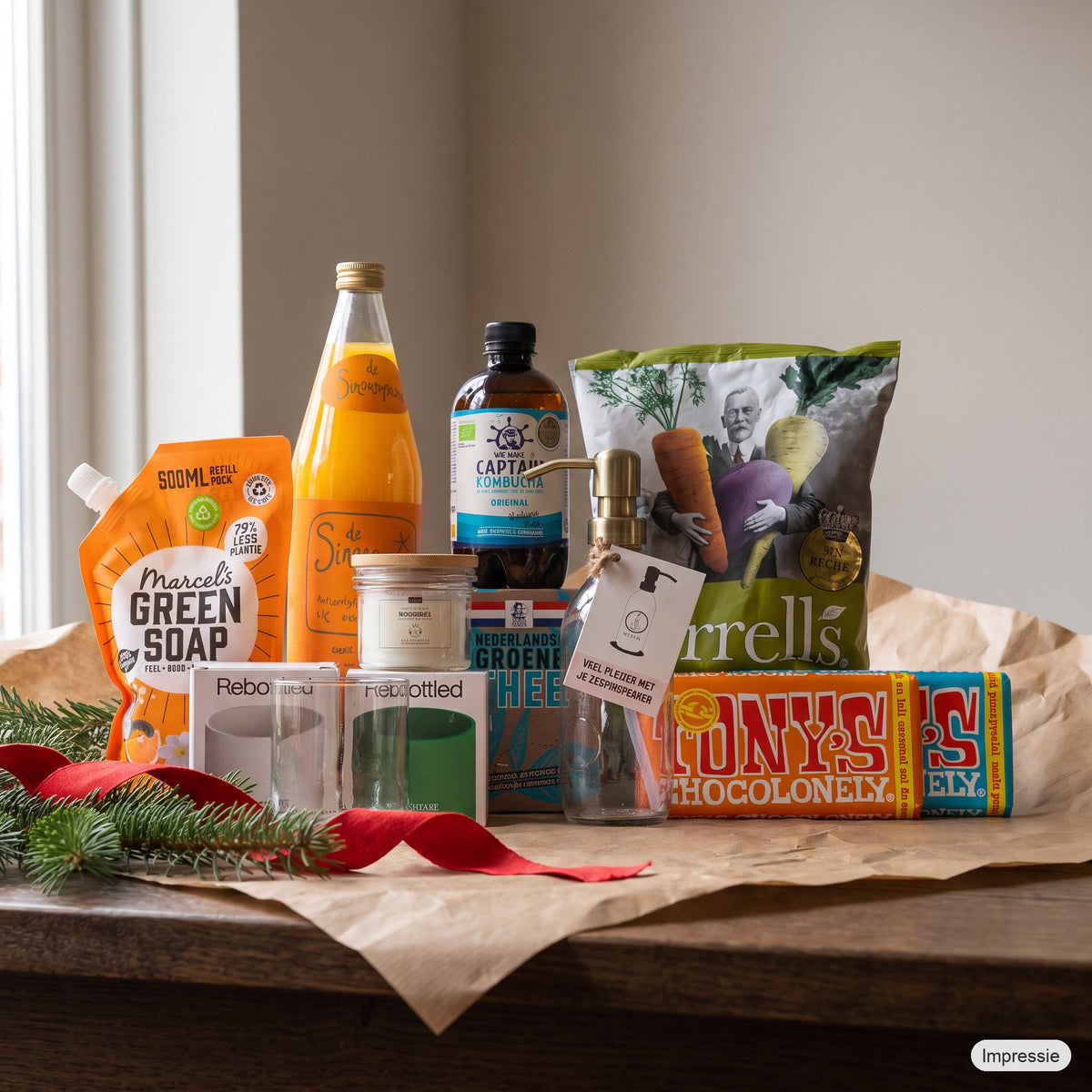 Classic Kerstpakket - M op een houten tafel met kraftpapier, dennentakken en een rood lint (impressie)