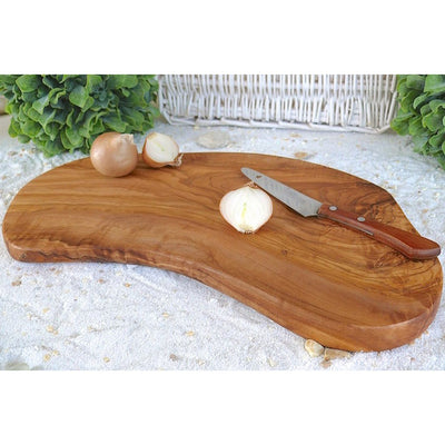 Rustieke plank van olijfhout met ui, knoflook en een mes, op wit zand
