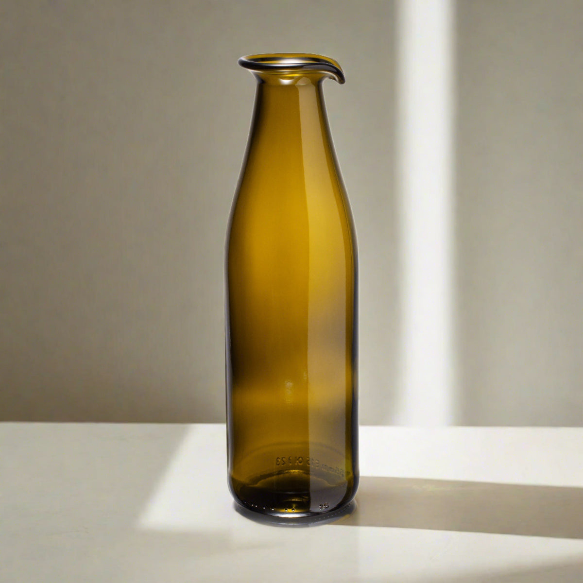 Olijfgroene karaf op tafel in het zonlicht
