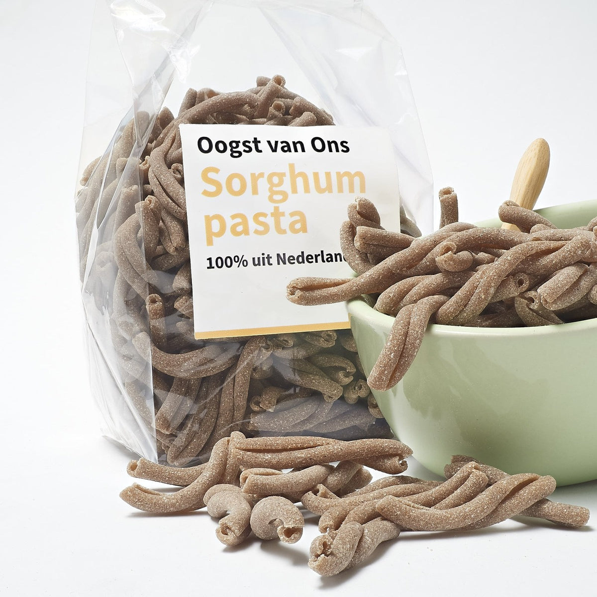 Strozzapreti van sorghum in een schaaltje met een houten lepel, naast de zak