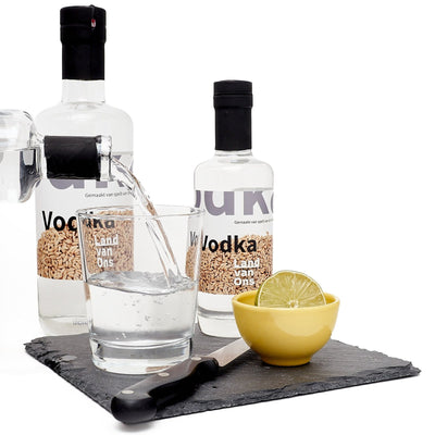 Vodka van Land van Ons wordt in een glas met ijs geschonken, met een halve limoen